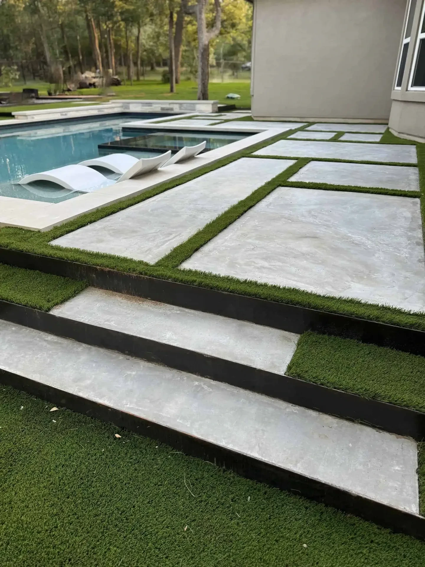 Artificial turf with concrete pads and steel edging by pool Austin TX