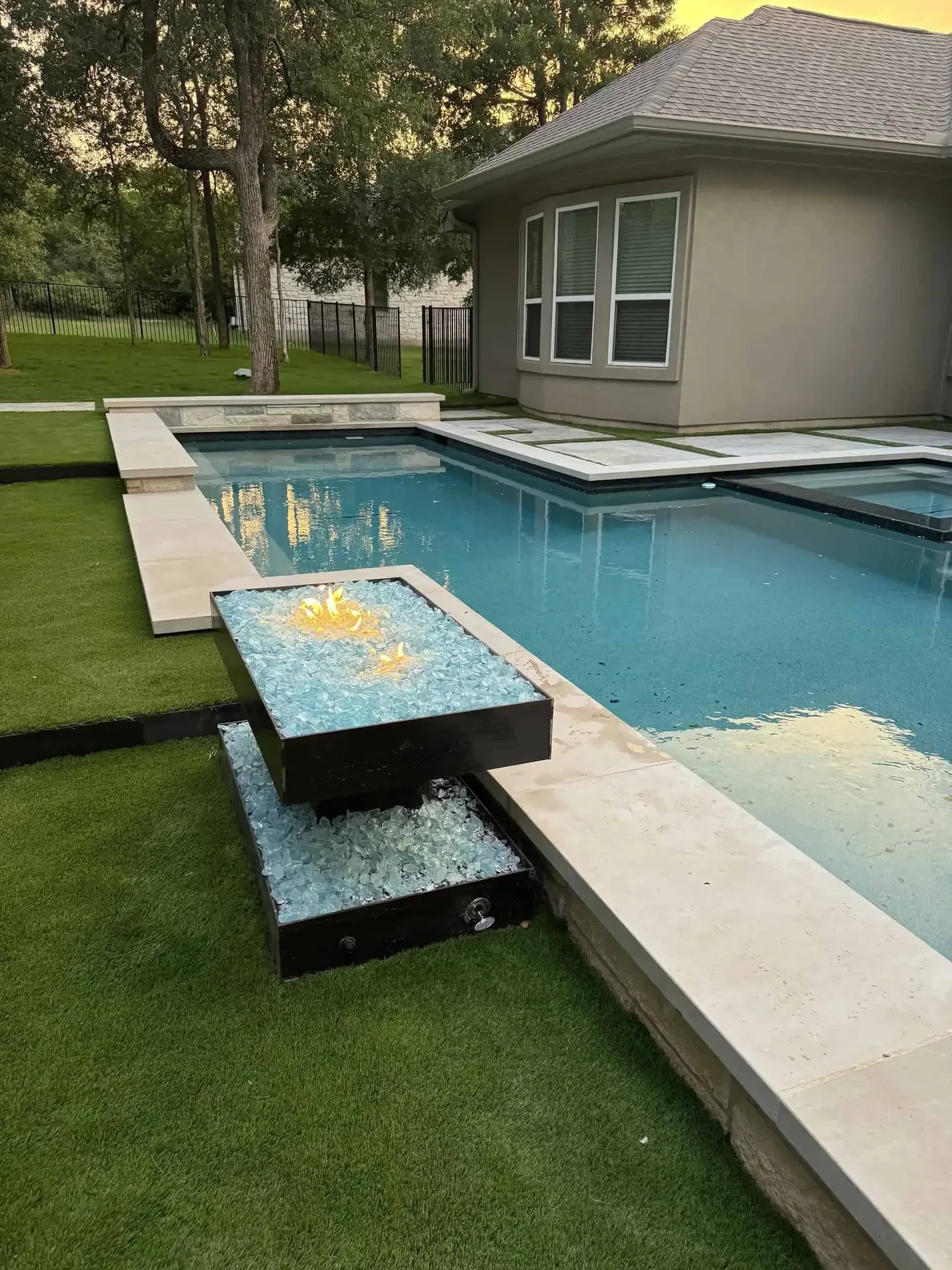 Floating boulder fire pit with propane plumbing on marbled concrete pad with FCOB perimeter lighting — Lakeway Austin TX