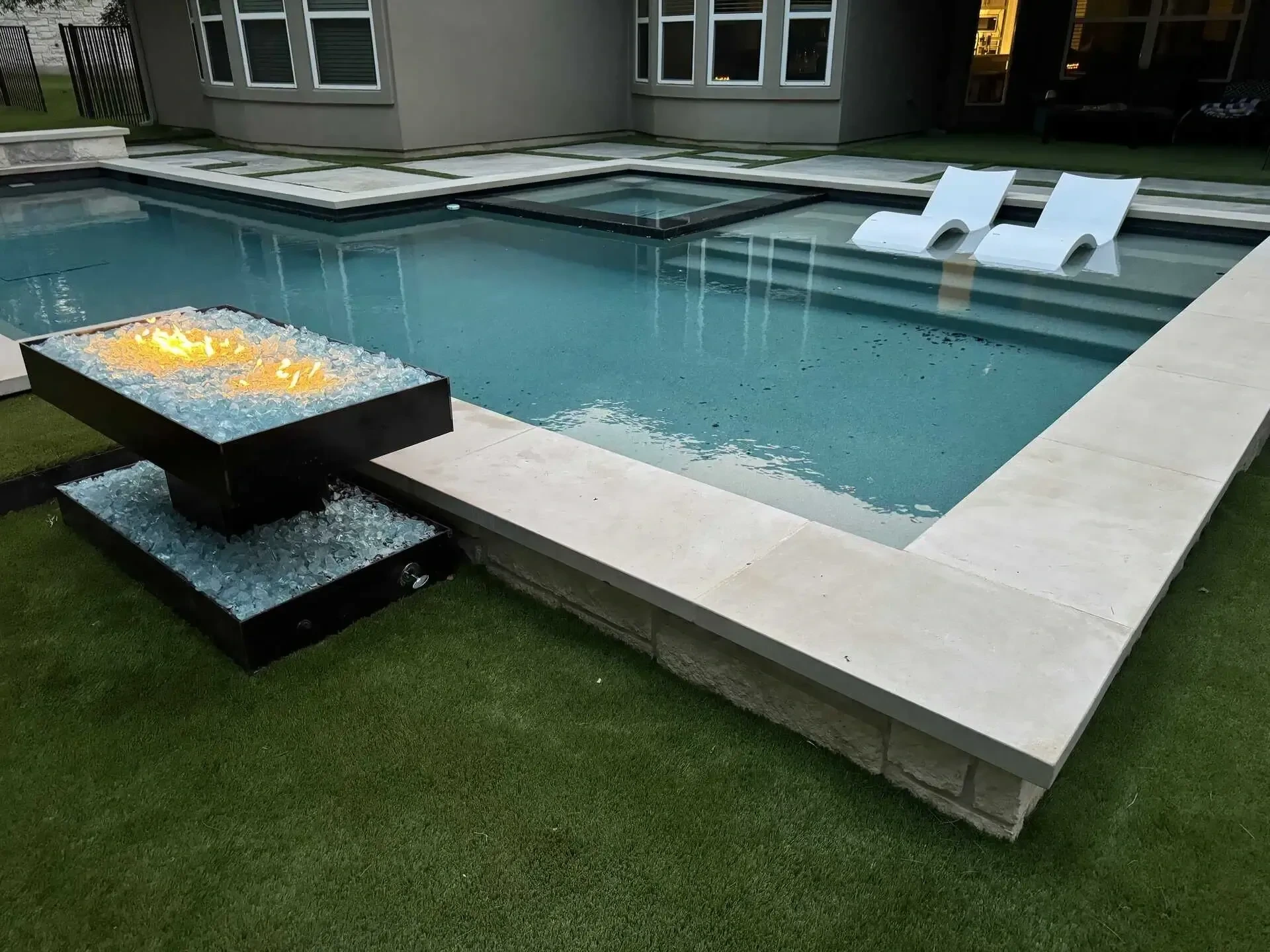 Diffused steel light box casting warm architectural glow at outdoor seating area with native plantings — Tarrytown Austin TX