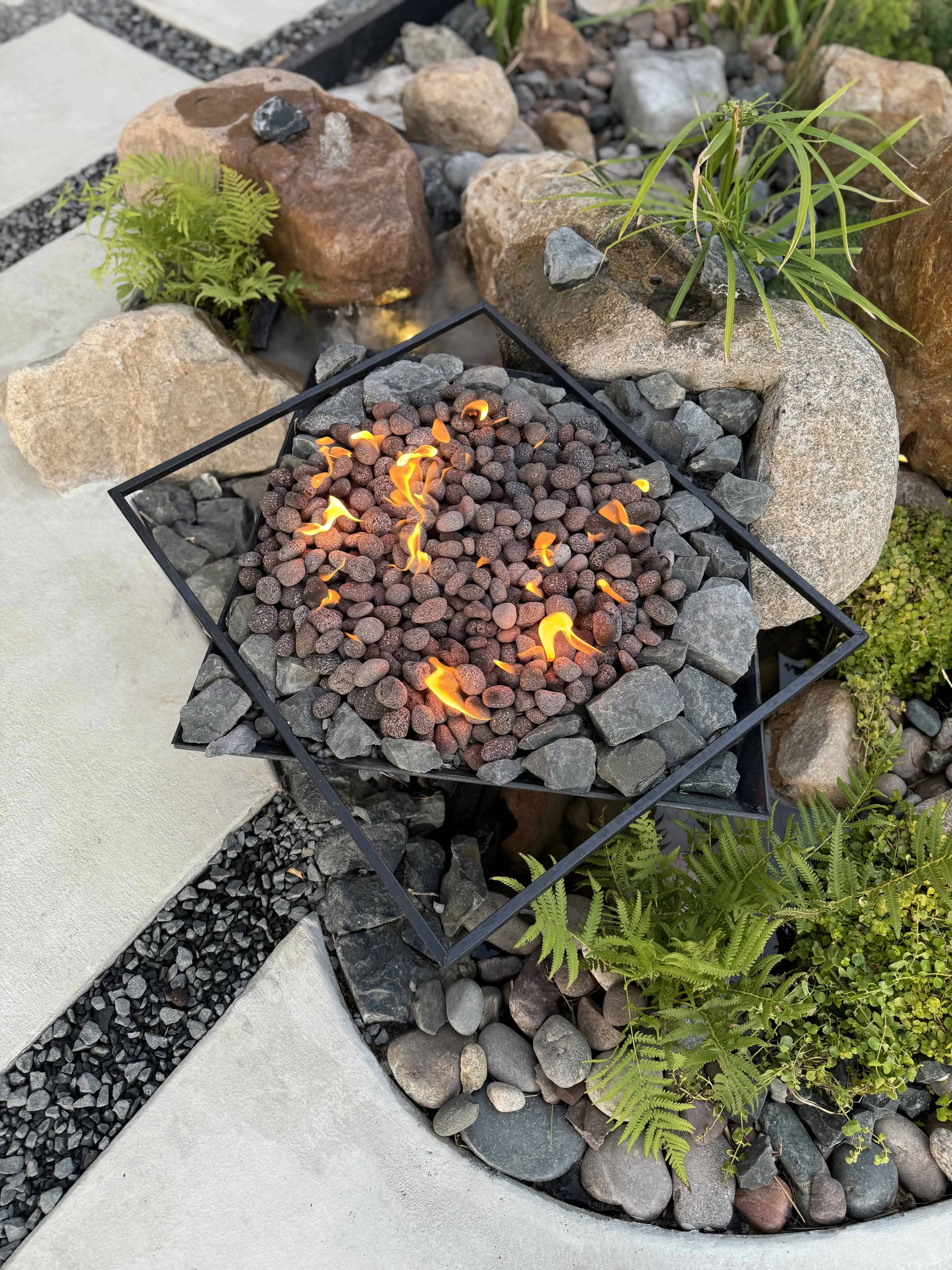 Overhead — diamond fire pit with volcanic rock burning, boulders, fern — Pflugerville TX