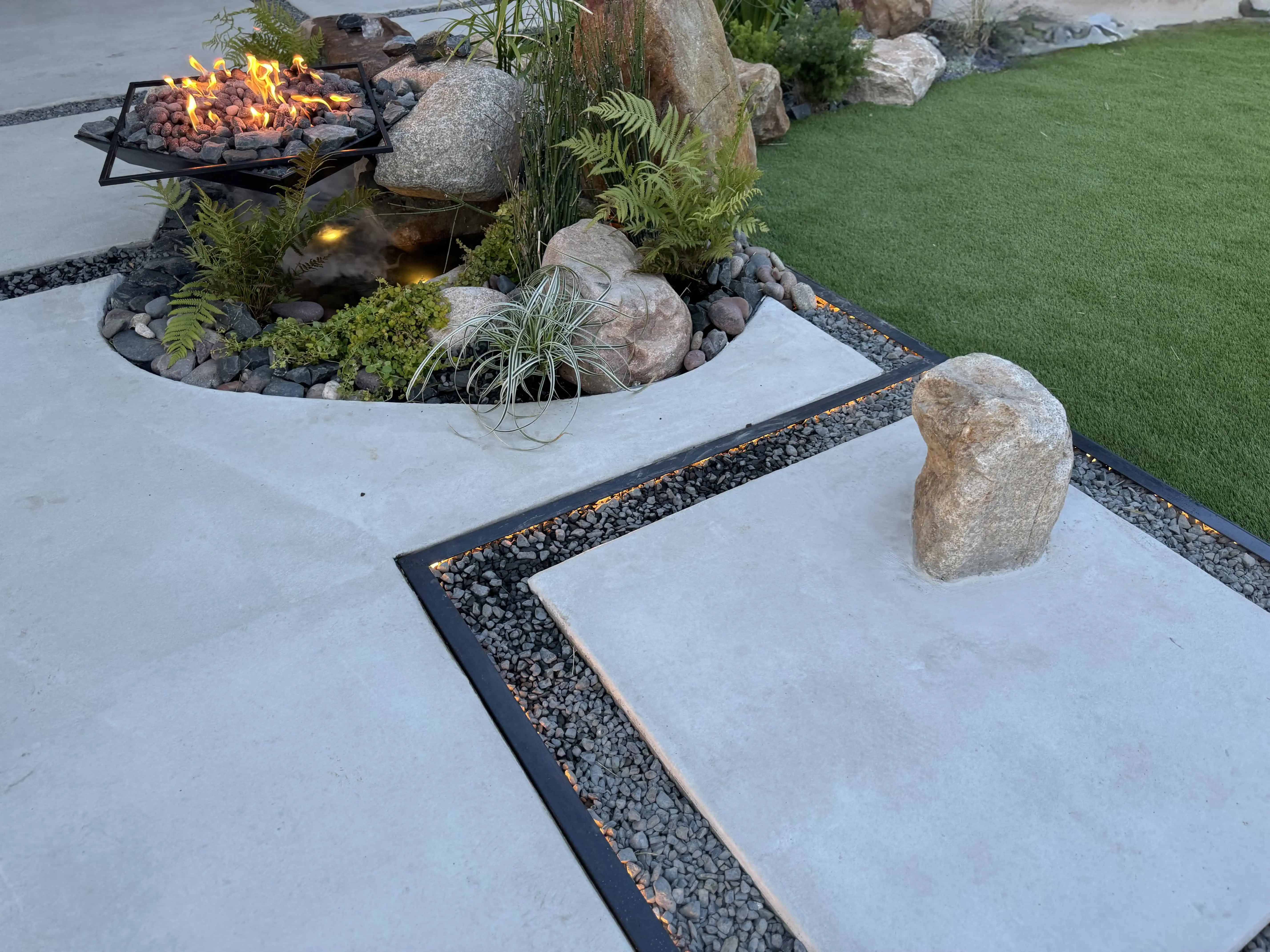 COB-lit paver joints with boulder fountain and fire pit in planting bed — Pflugerville TX