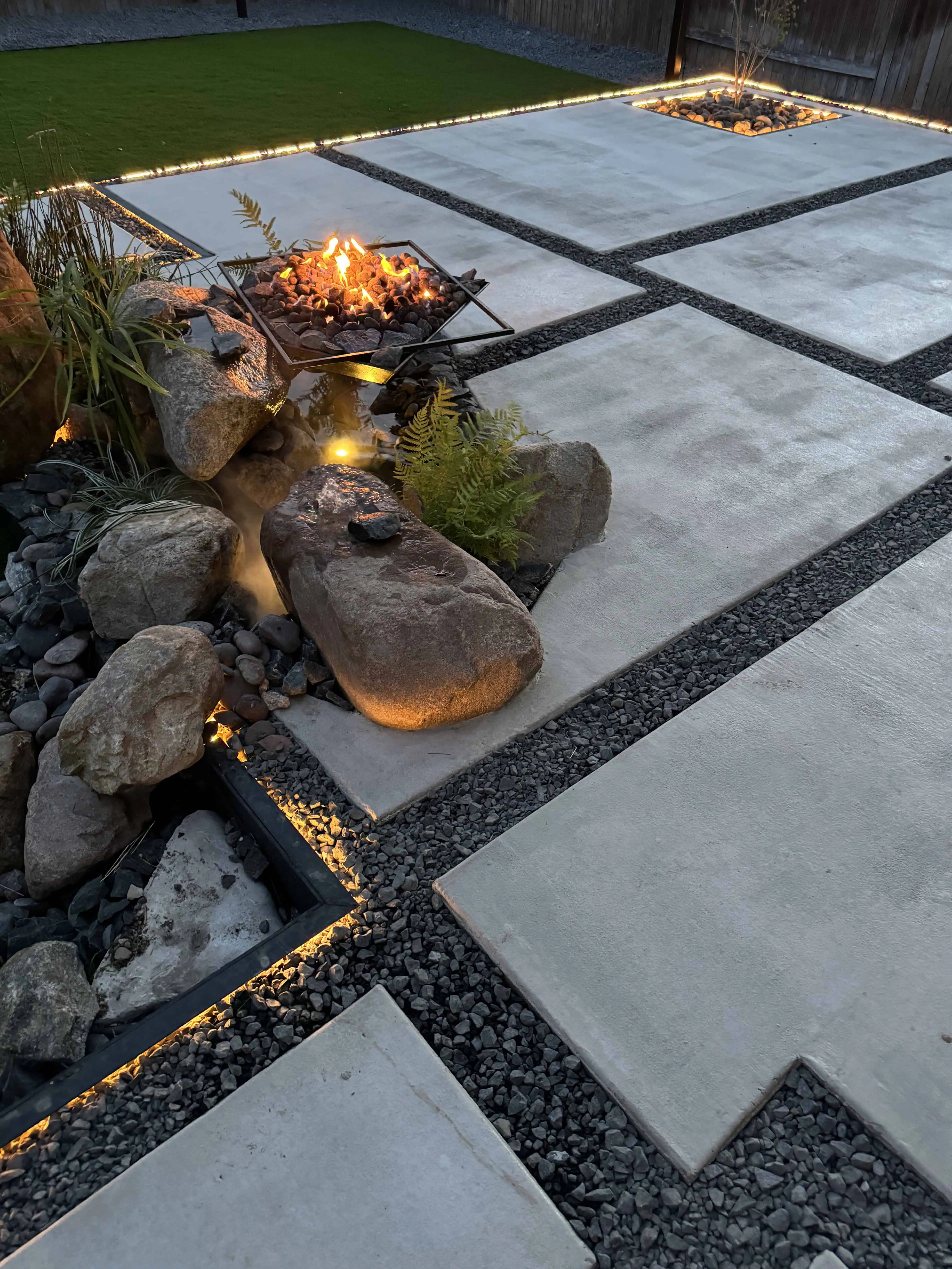 Wide elevated view — full patio with SureCrete pavers, COB-lit joints, fire pit, orchid tree planter — Pflugerville TX