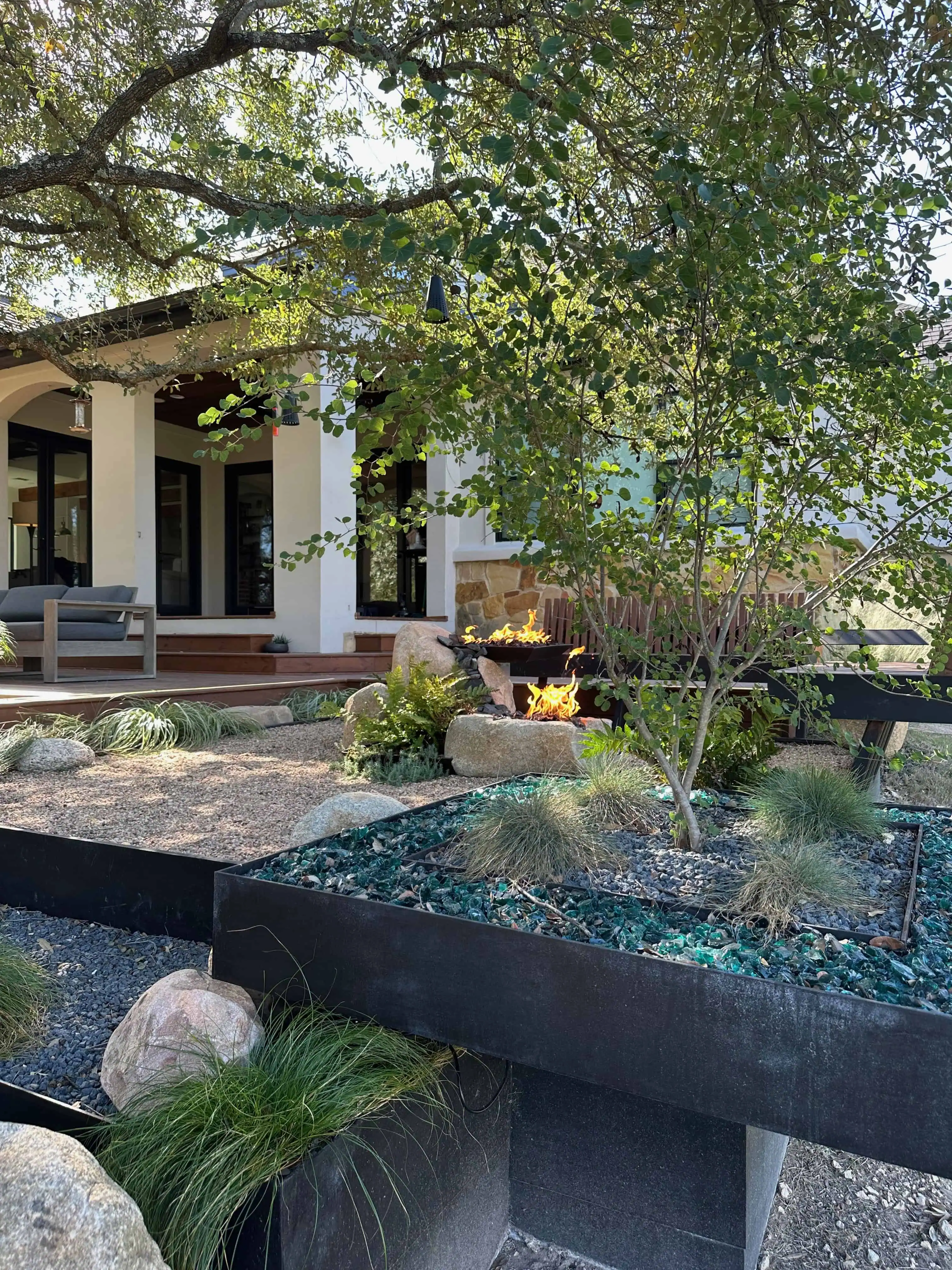 Cantilevered turquoise glass planter under live oak canopy with fire pit — Circle C Austin TX