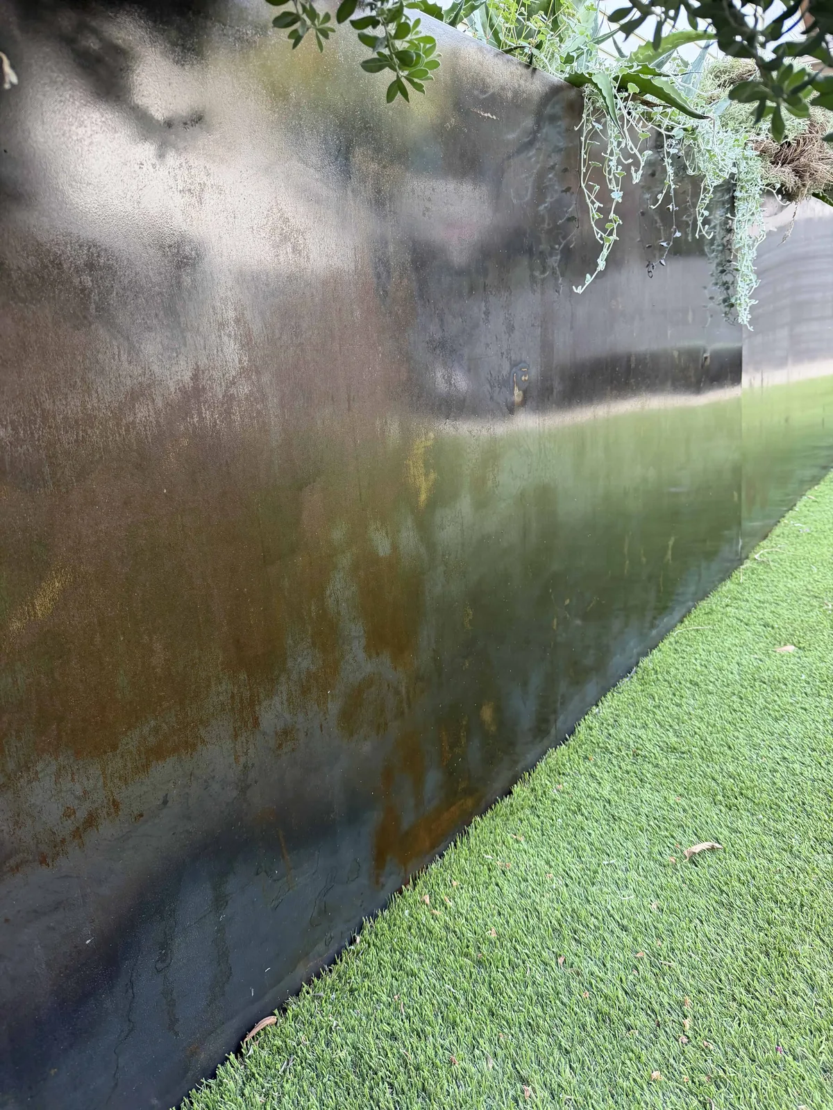 Darkened steel retaining wall in backyard with turf — Tarrytown Austin TX