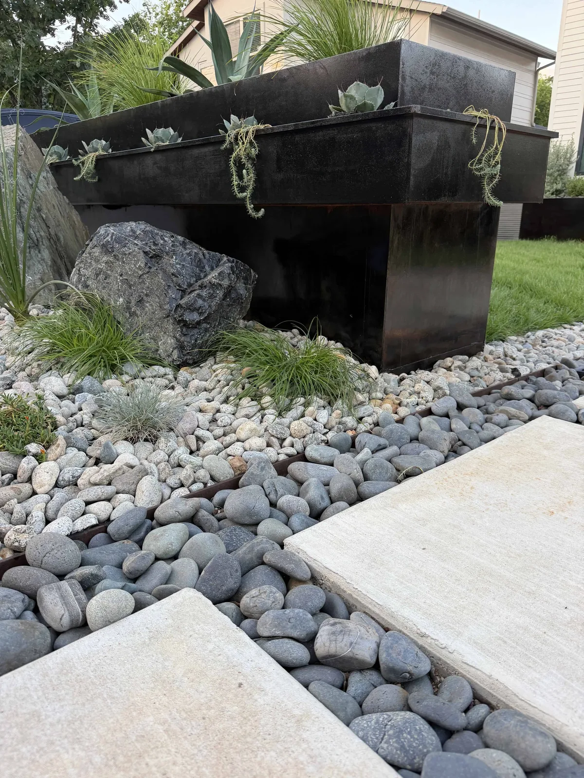 Cantilevered steel planter with artichoke agave, blue spruce sedum, Mexican beach pebbles, and concrete stepping stones — Tarrytown Austin TX