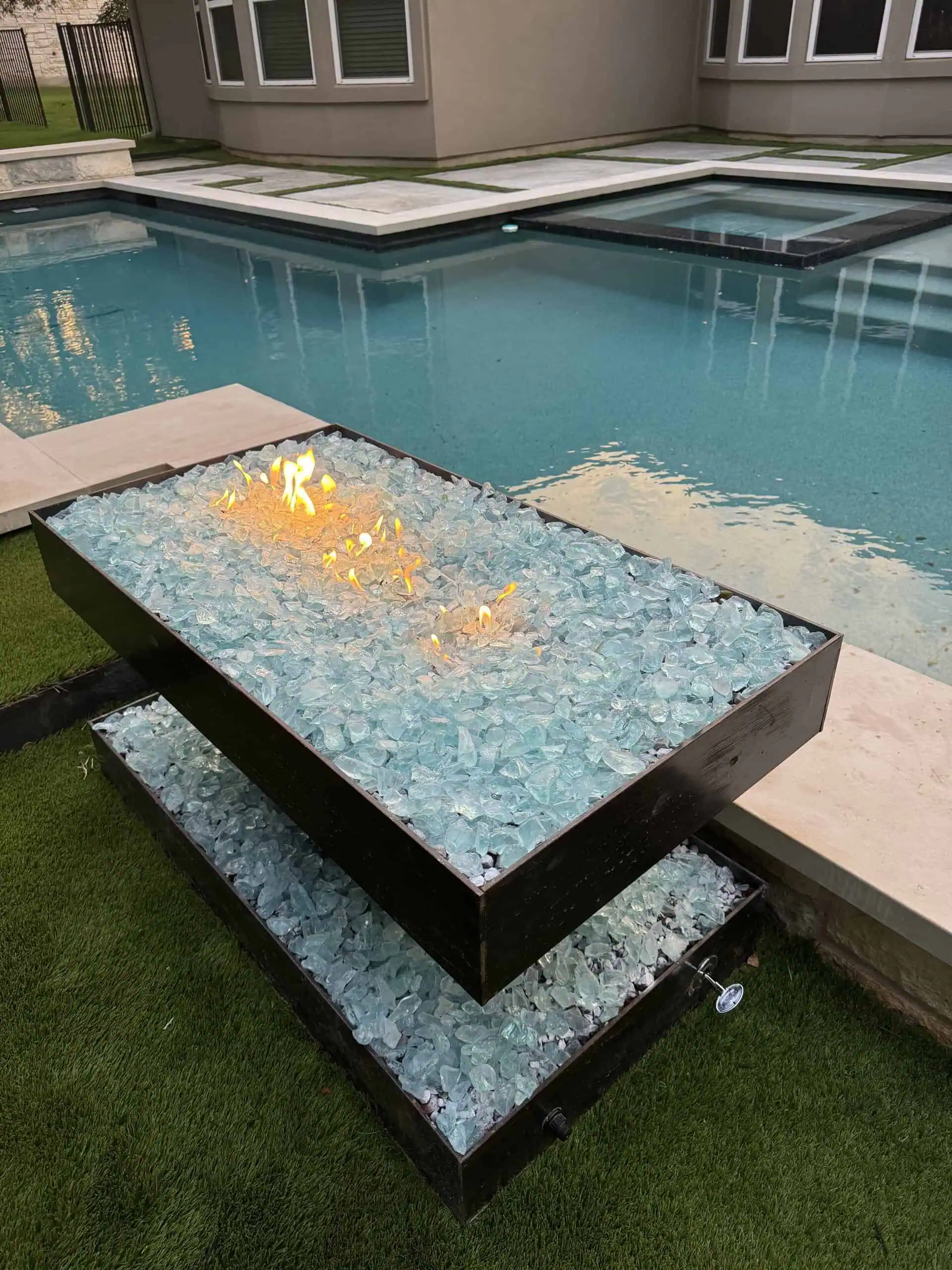 Poolside welded steel fire pit with aqua fire glass close-up — Austin TX