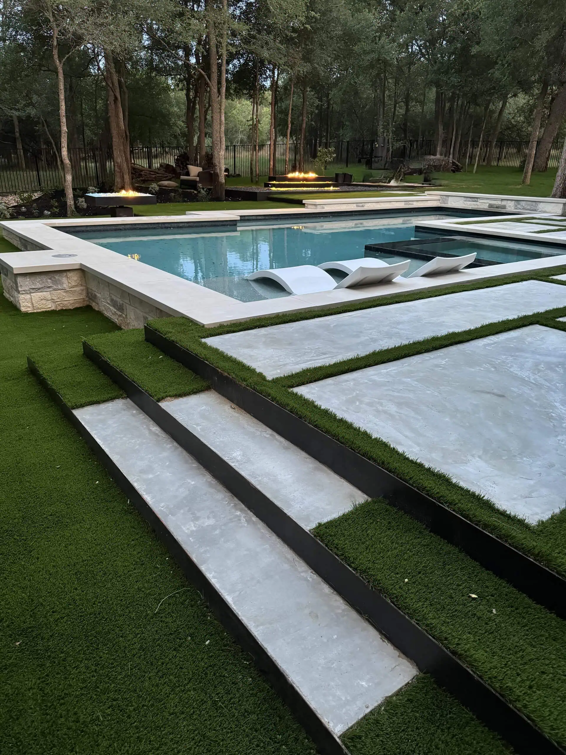 Wide dusk overview — large format pavers, turf, pool, both fire pits — Austin TX