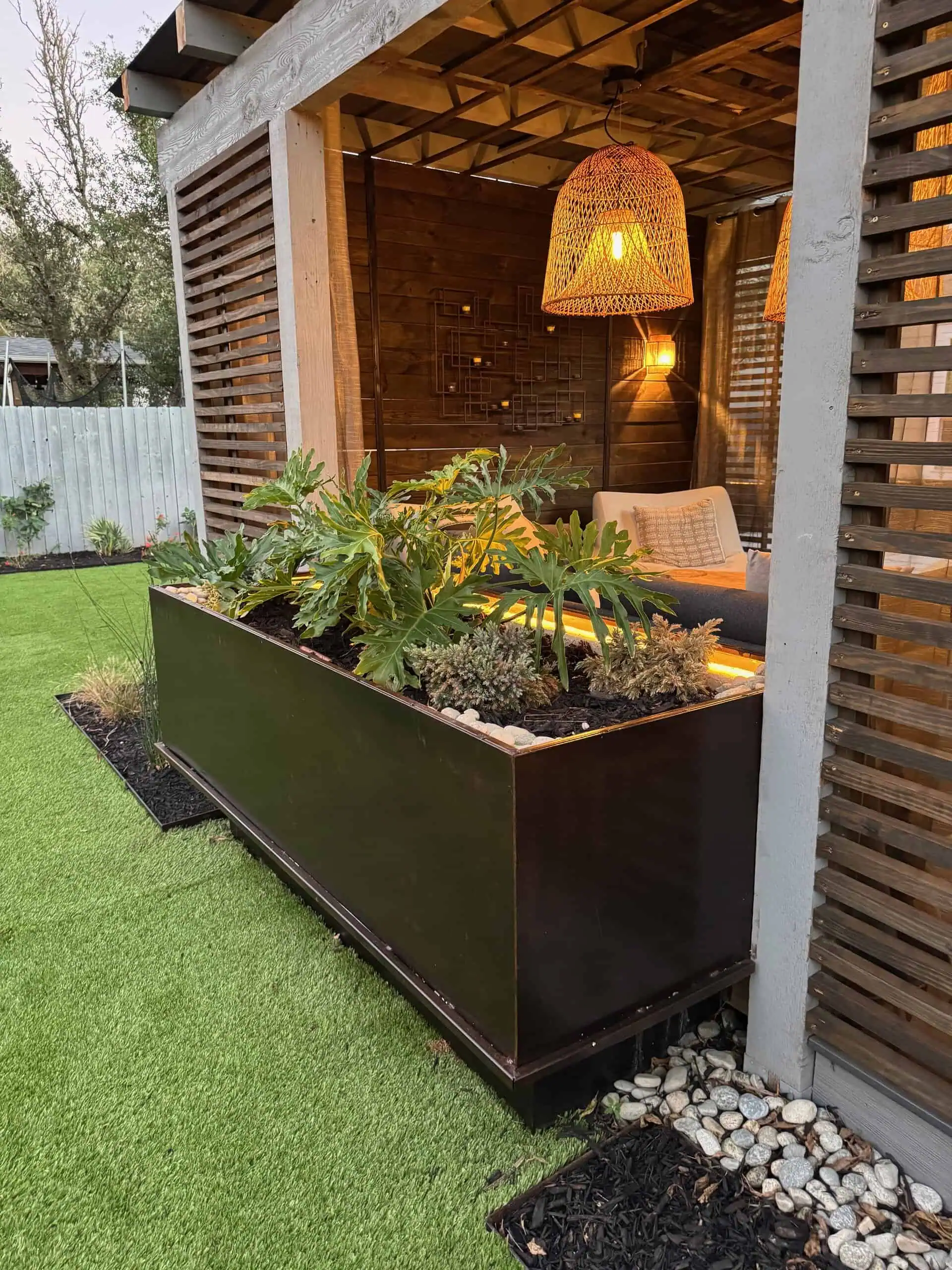 Hopeland after — Dekorators Sea Salt deck, custom-cut steel triangle pergola, boulder fire pit step, COB-lit cantilevered planters, Circle C, Austin TX