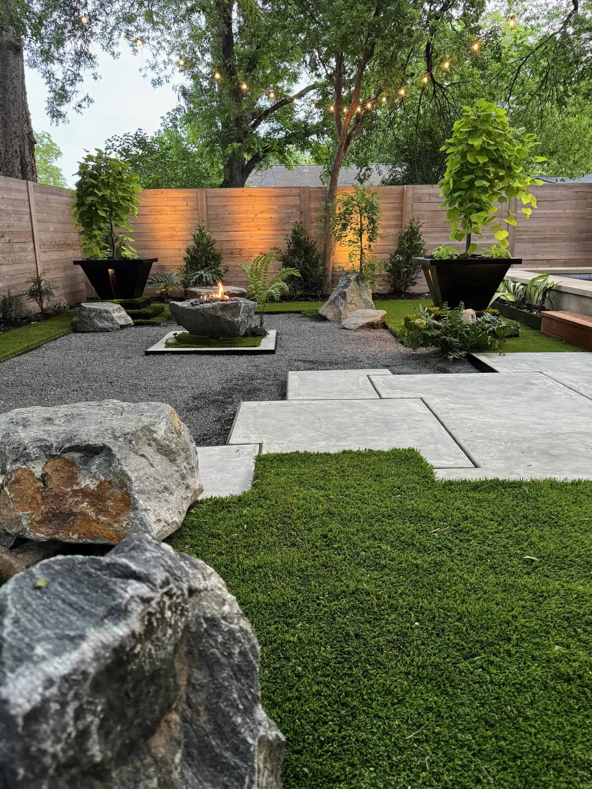Full yard overview at dusk — gravel, turf, boulders, planters — Austin TX
