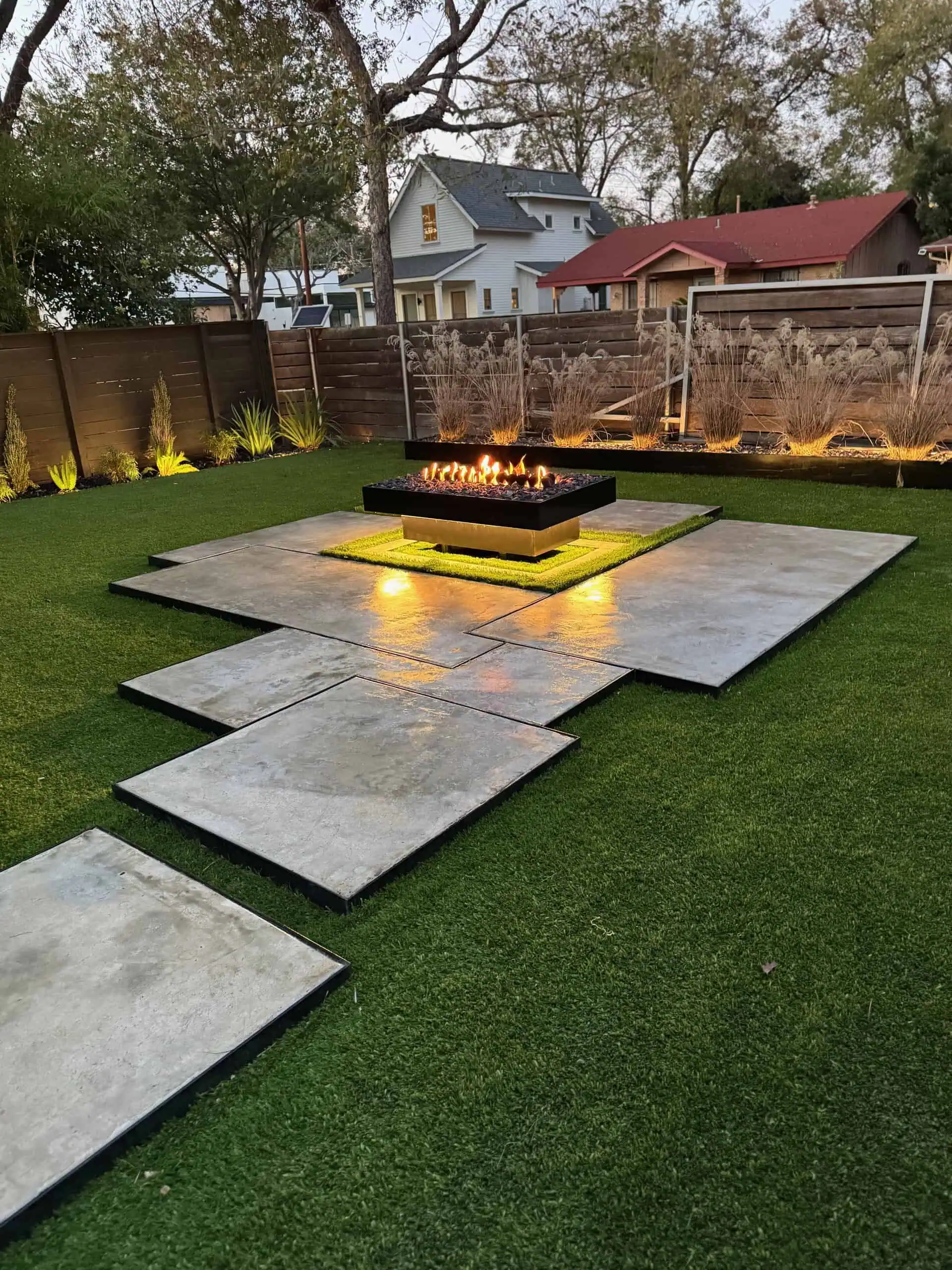 Wide twilight view — concrete poured to look like marble, floating fire pit, planting beds lit — Austin TX