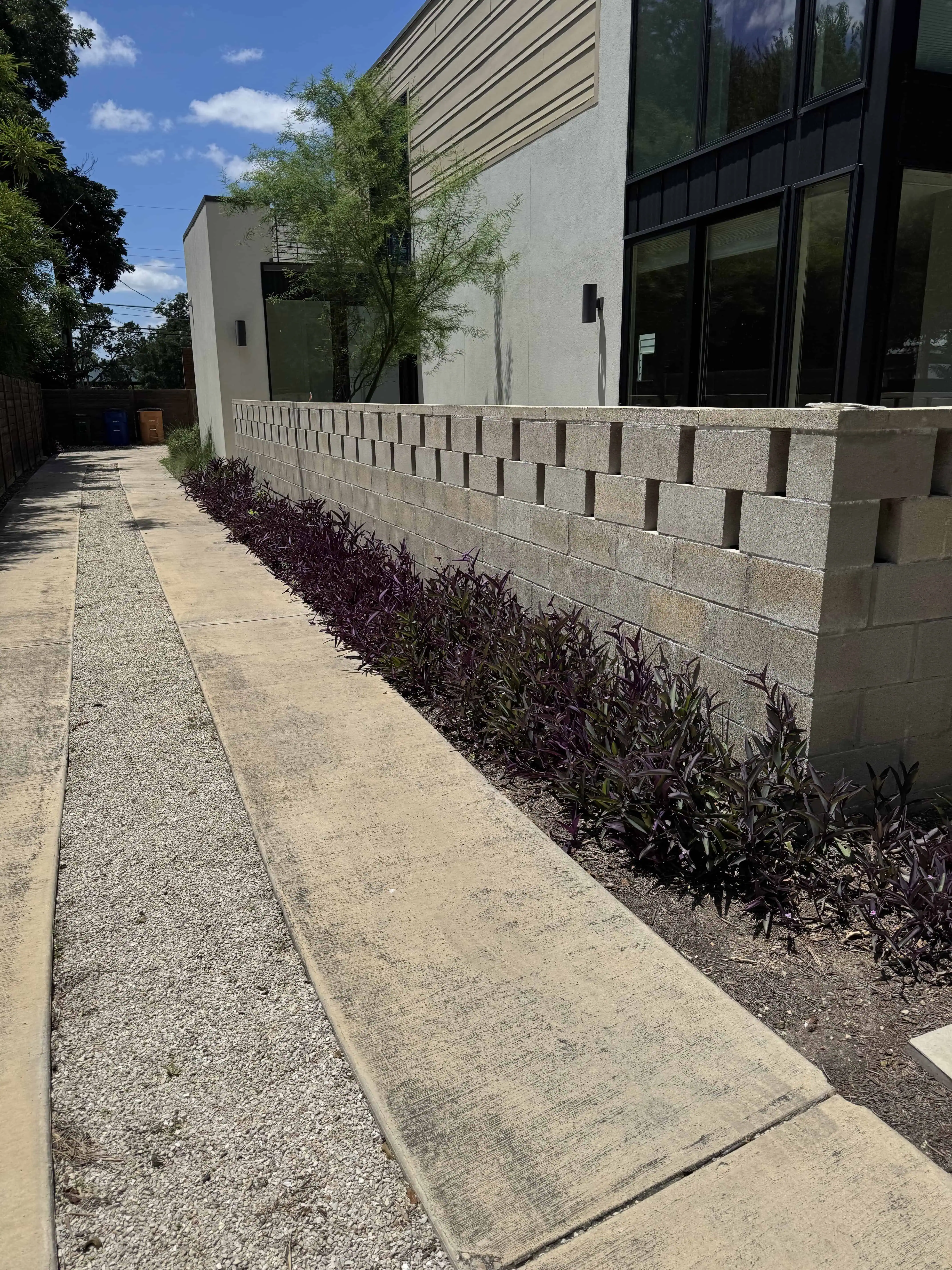 Riverview before — CMU block wall bisecting the yard, gravel path — Austin TX